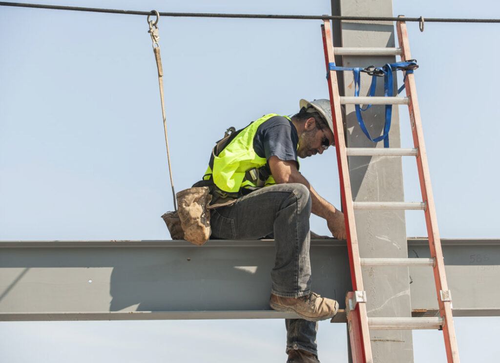 Construction working sitting on beam next to ladder