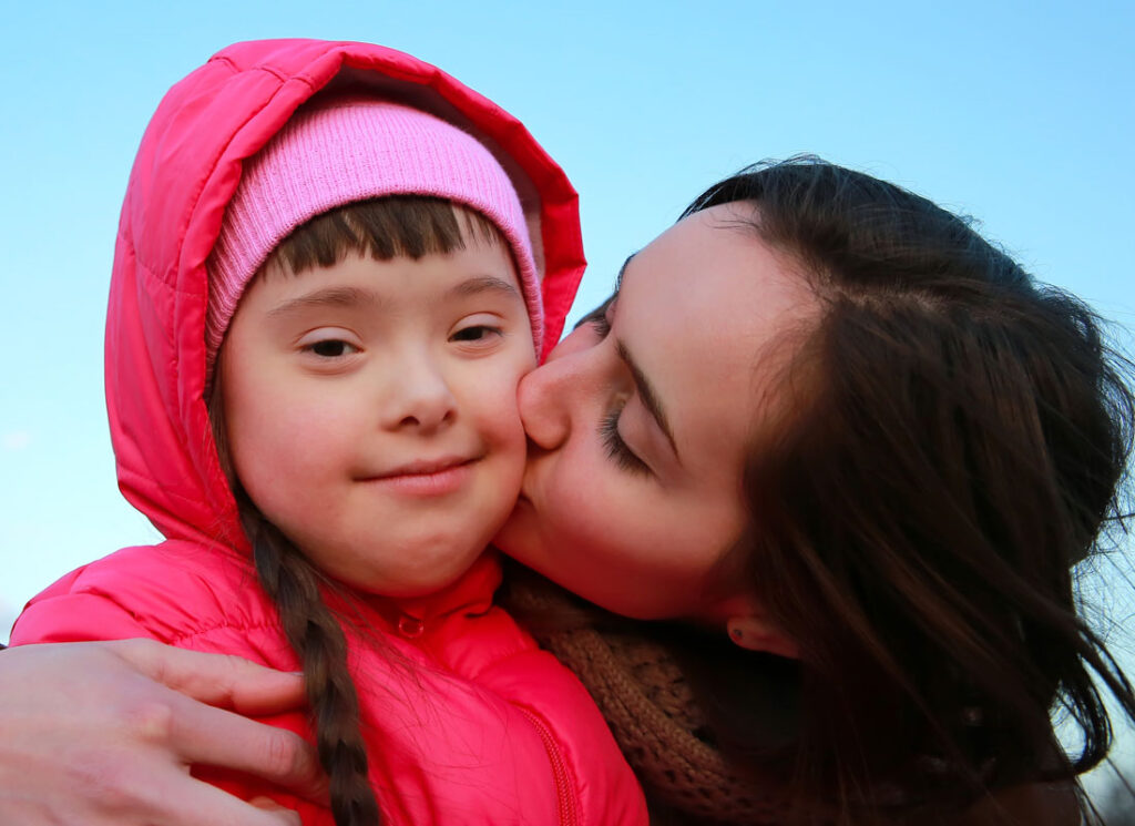 Woman kissing young girl on the cheek