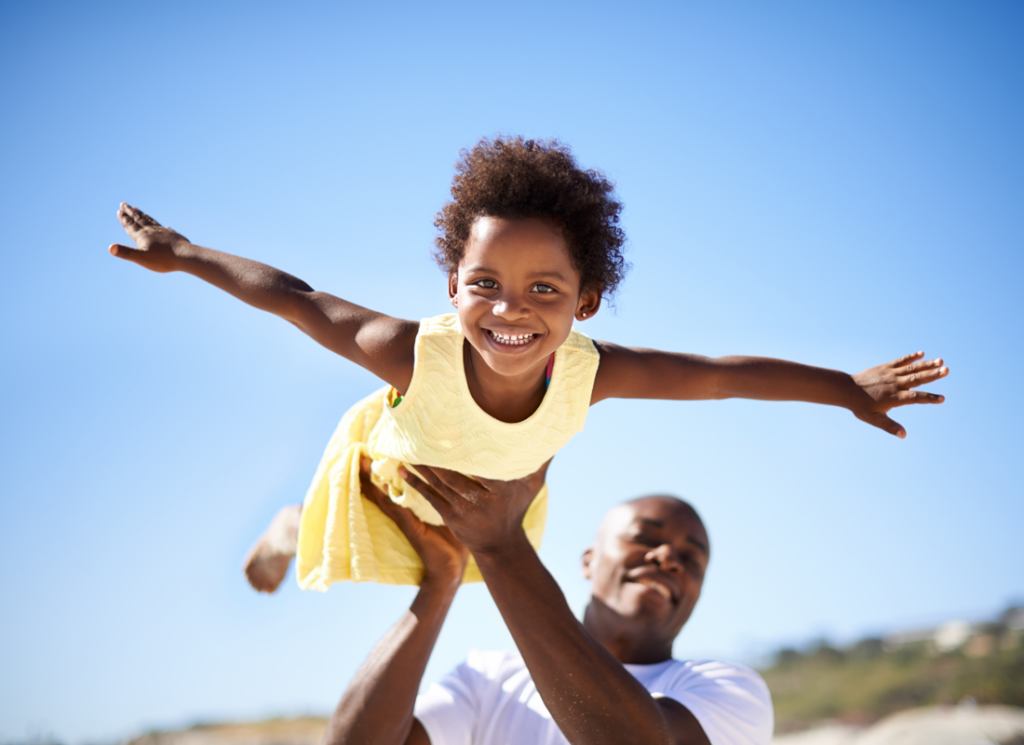 man holding child in air with arms out
