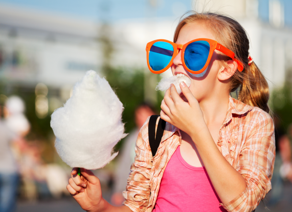 Young girl with giant, novelty sunglasses eating cotton candy