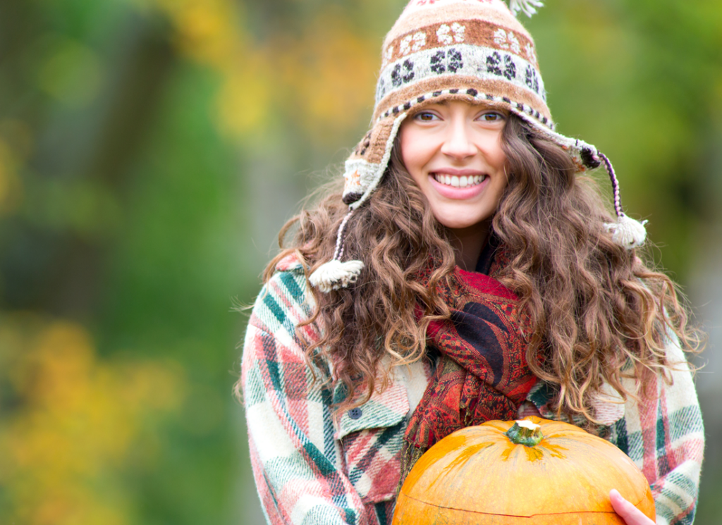 girl with patterned hat holding pumpkin