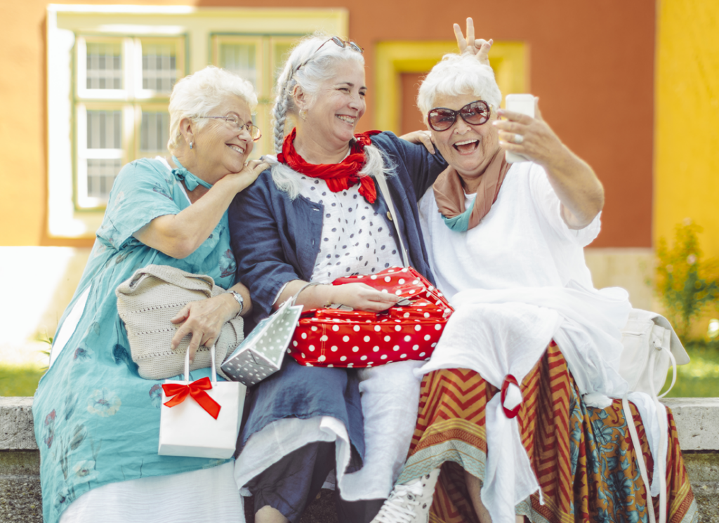 3 senior women sitting on a bench laughing together