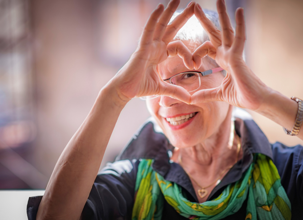 women holding up hand with fingers in shape of a heart