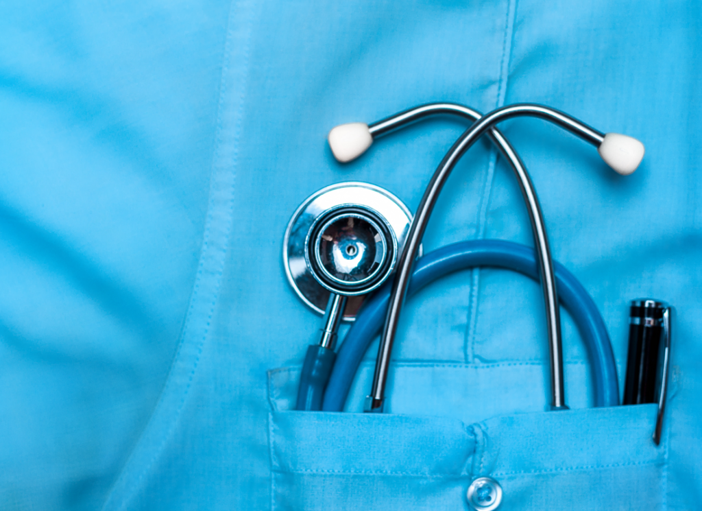 Stethoscope and light pen in pocket of blue scrubs
