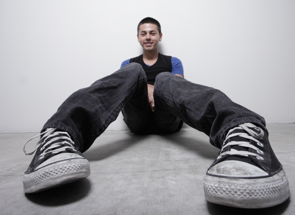 man sitting against wall with converse sneakers